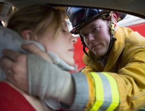 Firefighter putting neck brace on injured woman in car accident.